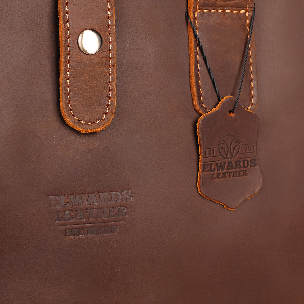 Elwards Leather logo and vintage tag on a handcrafted brown leather bag.