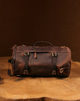 Flat-lay of a brown vintage leather backpack on a wooden surface, highlighting its rugged yet elegant design