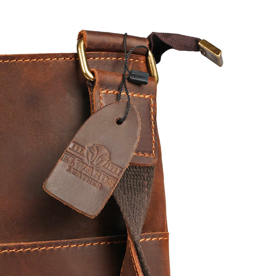 Close-up of golden hardware detailing and Elwards Leather logo on the vintage brown crossbody leather bag.