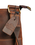 Close-up of golden hardware detailing and Elwards Leather logo on the vintage brown crossbody leather bag.