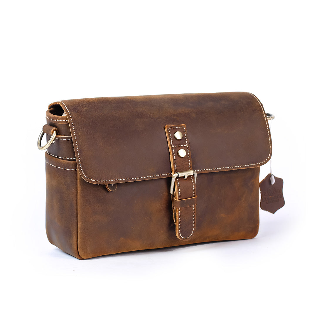 Brown leather bag with a strap on a white background