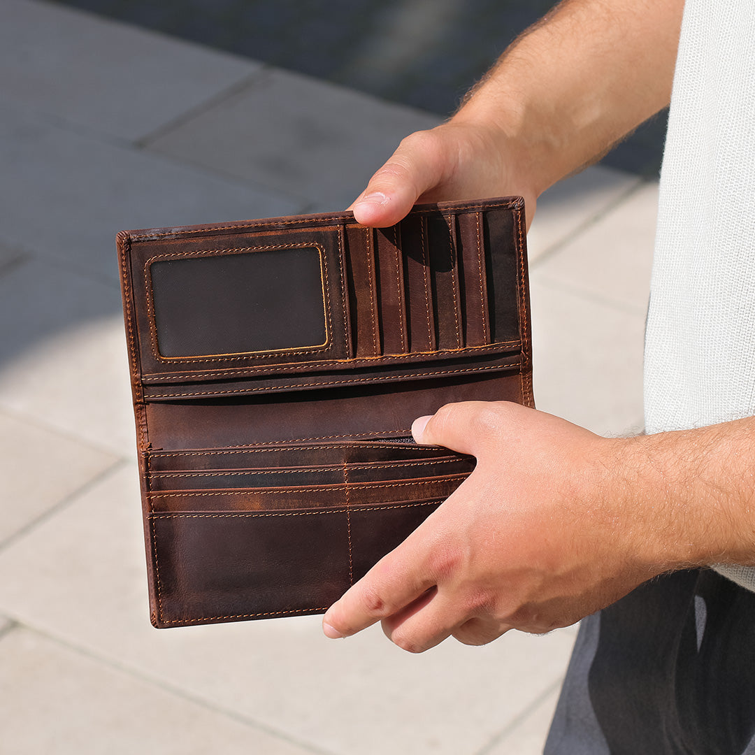 Brown leather wallet held open by a person's hands on a light background