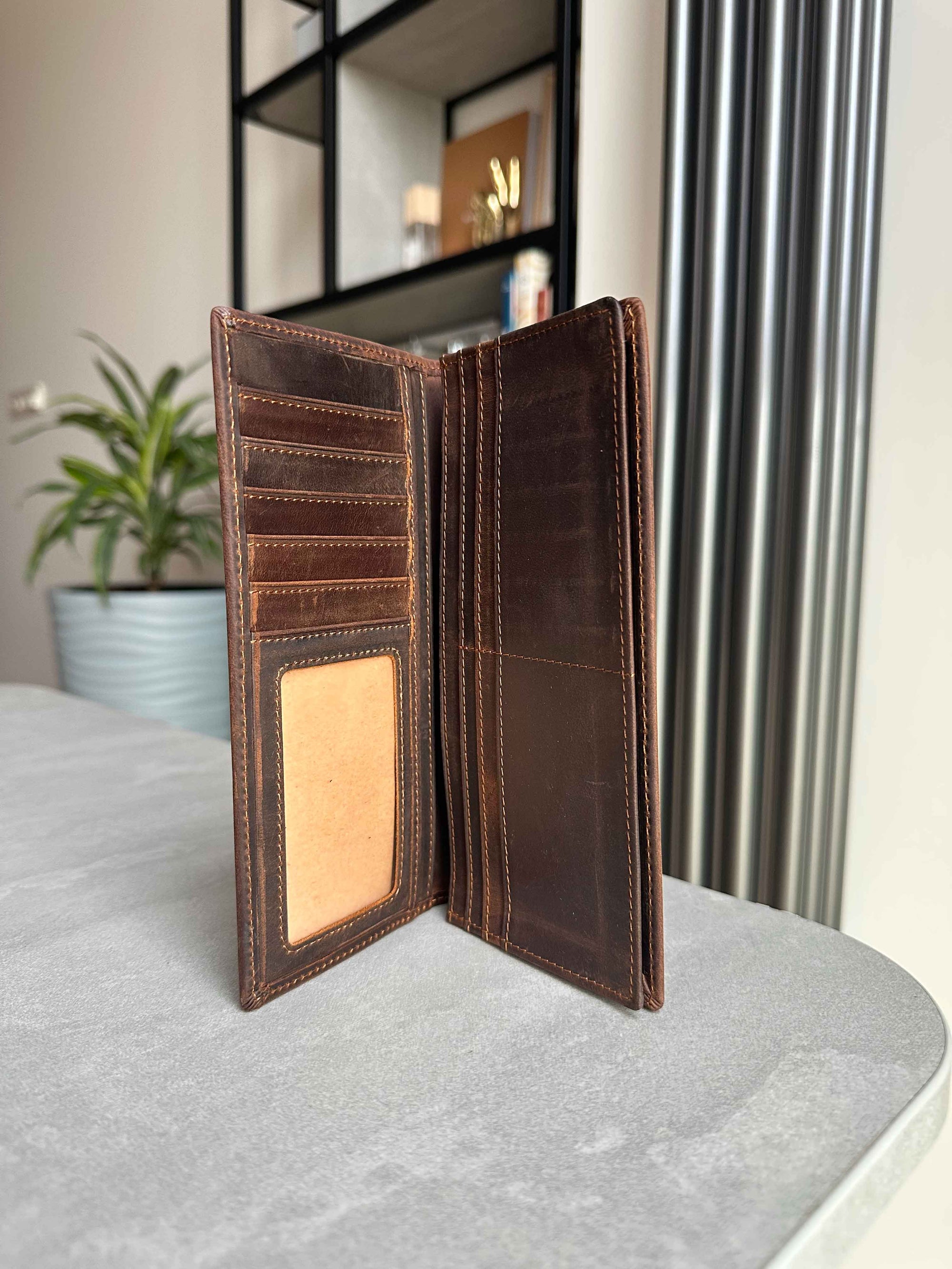 Brown leather wallet open on a gray surface with a blurred indoor background