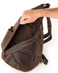 Brown leather backpack being held by a hand on a white background