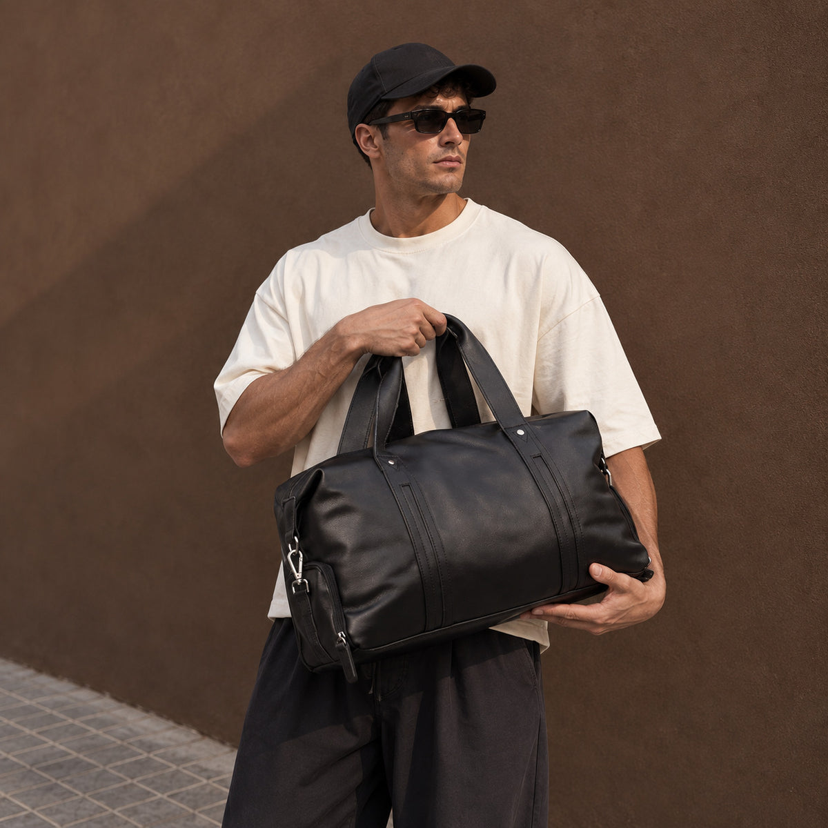 Large black leather duffle bag for men with dual carry handles, detachable shoulder strap and spacious travel design