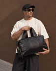 Large black leather duffle bag for men with dual carry handles, detachable shoulder strap and spacious travel design