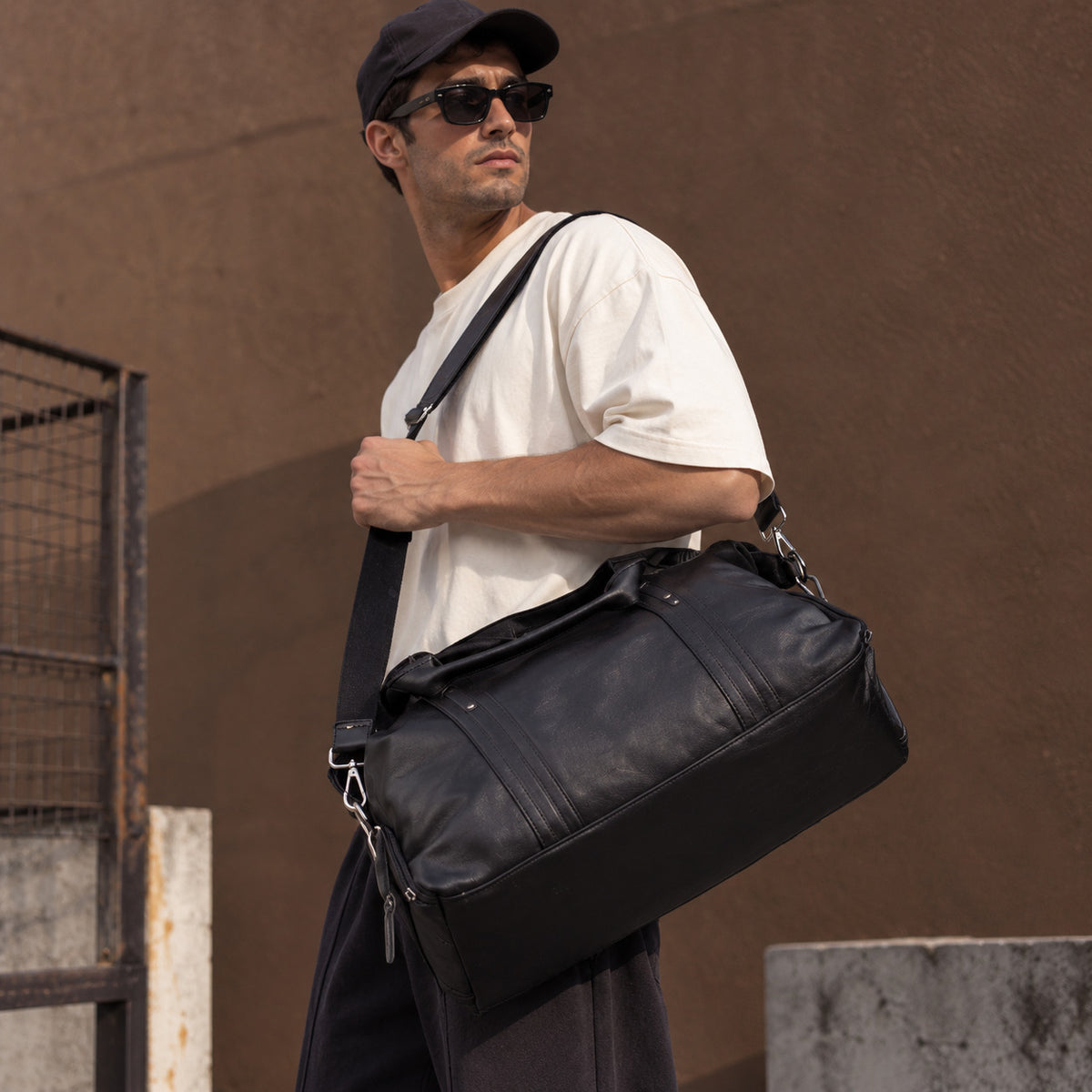 Large black leather travel duffle bag for men with reinforced carry handles, shoulder strap and structured base