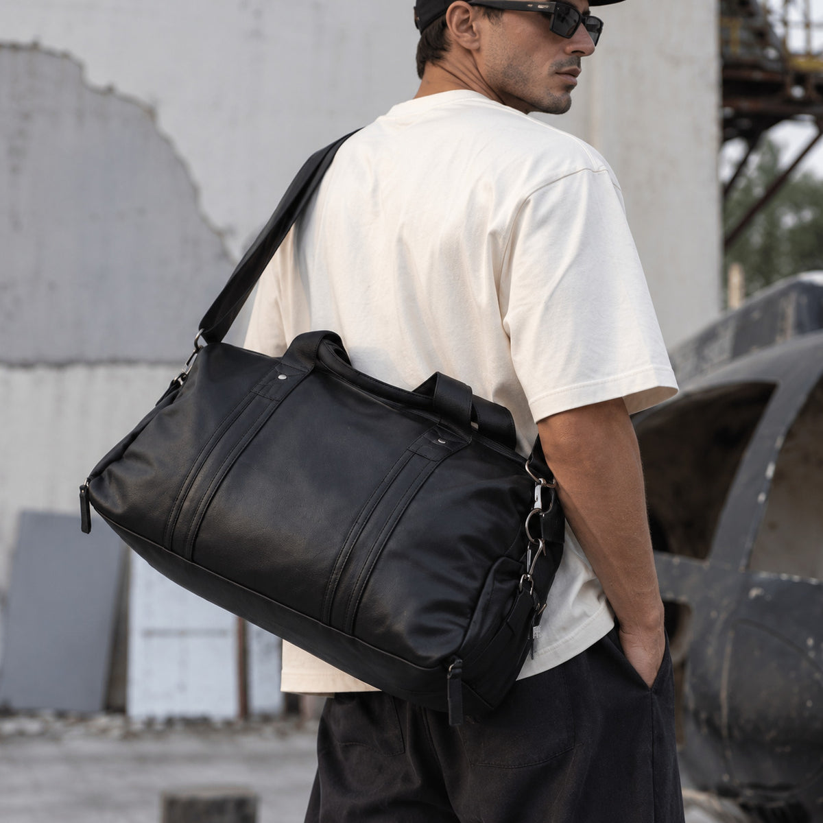 Large black leather weekender bag for men with wide adjustable shoulder strap, top handles and roomy main compartment