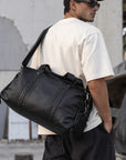 Large black leather weekender bag for men with wide adjustable shoulder strap, top handles and roomy main compartment