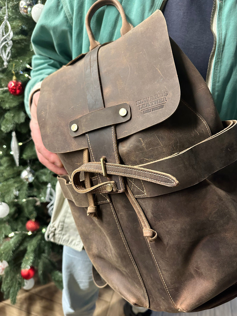 Brown leather backpack worn by a model, highlighting its vintage design and comfort for everyday use.