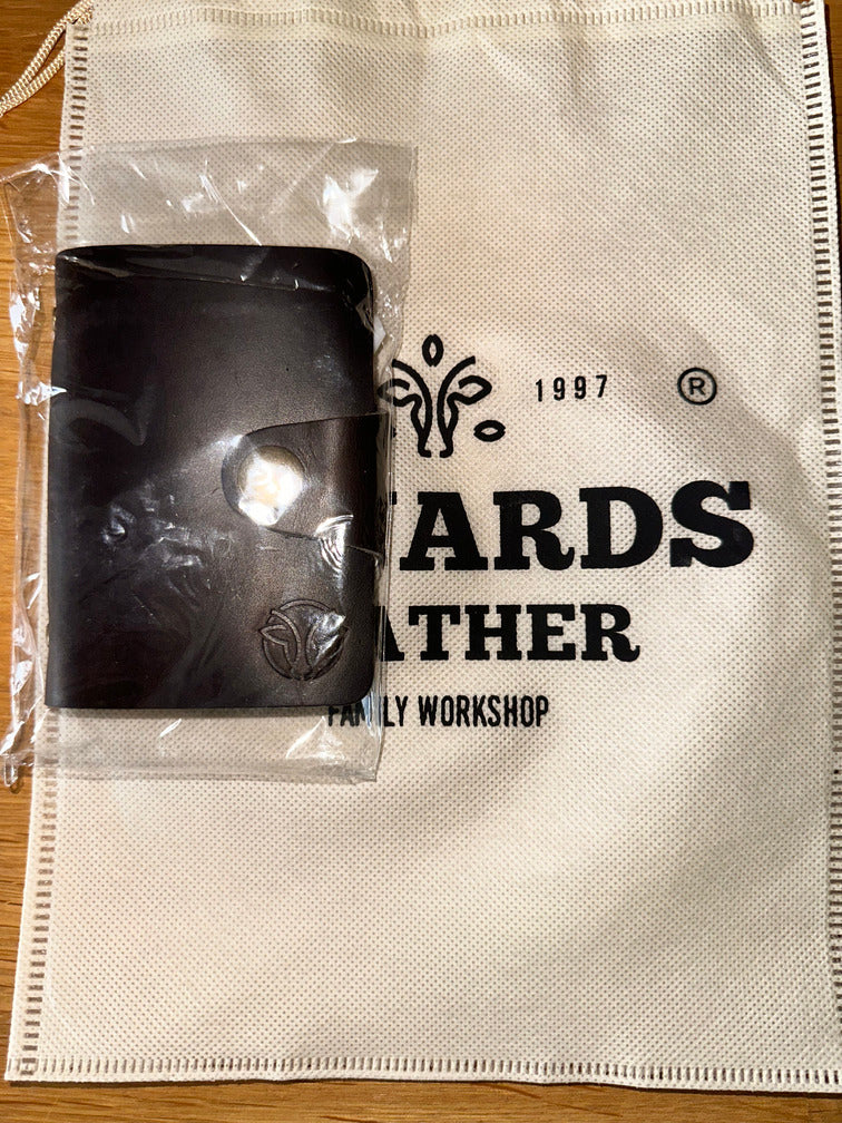 Leather card holder packed in a soft branded pouch, showcasing its premium craftsmanship in dark brown leather.