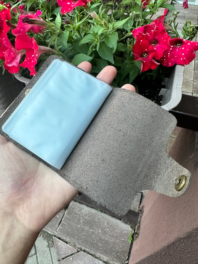 Leather card holder open with card slots, featuring a soft brown interior and button clasp for secure closure.