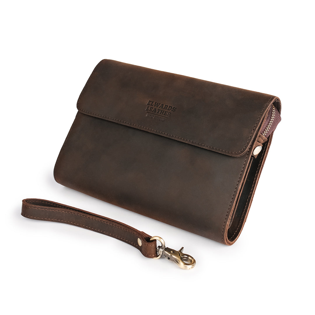 Angled view of a dark brown leather wrist bag with a detachable leather strap, perfect for versatile styling.