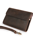 Angled view of a dark brown leather wrist bag with a detachable leather strap, perfect for versatile styling.