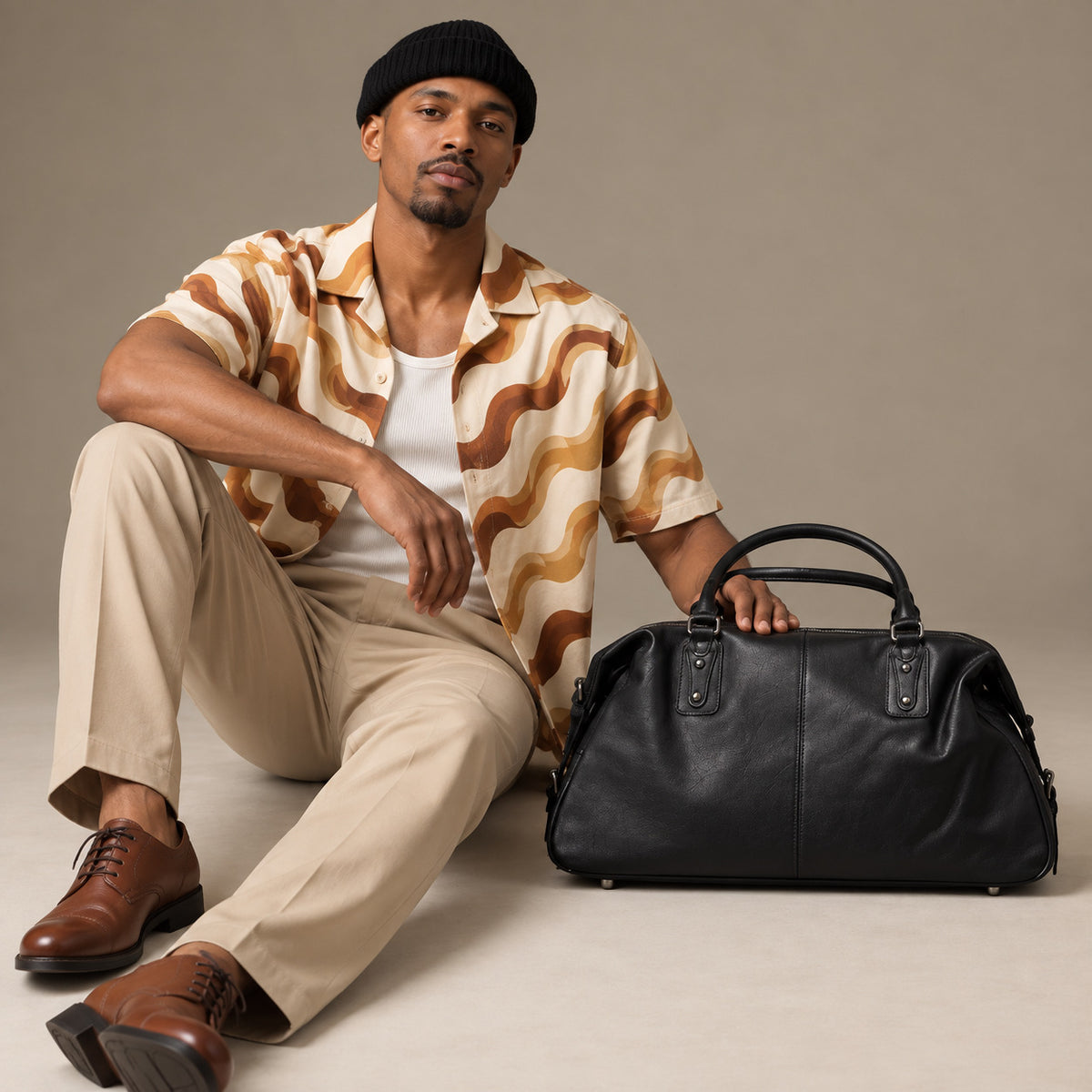Luxury black leather duffle bag for men with rounded weekender shape, reinforced handles and spacious carry-on design