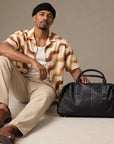 Luxury black leather duffle bag for men with rounded weekender shape, reinforced handles and spacious carry-on design