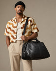 Luxury black leather duffle bag for men with top handles, adjustable shoulder strap and spacious weekender design