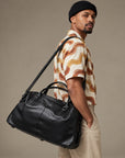 Luxury black leather travel duffle bag for men with top handles, detachable shoulder strap and roomy overnight design