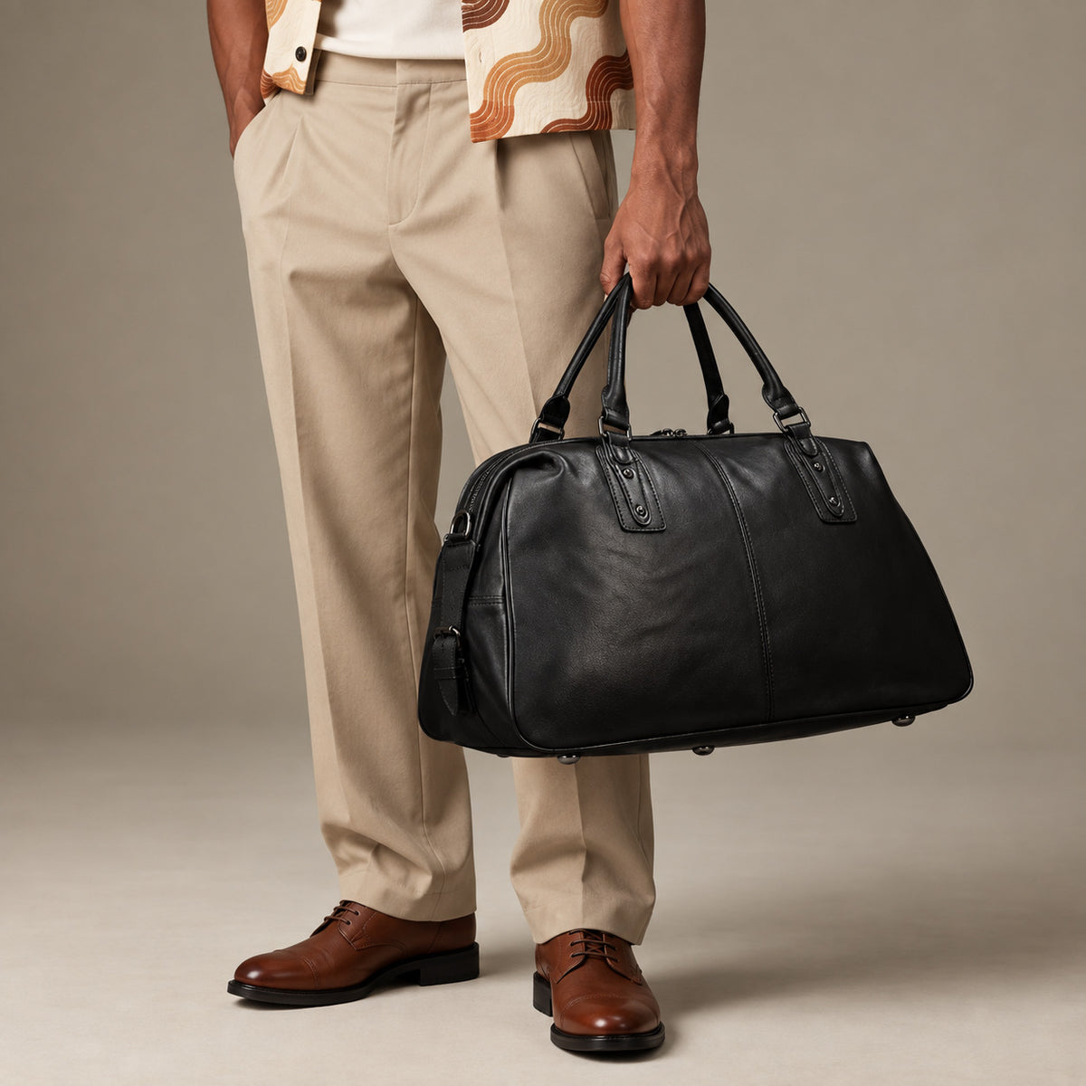 Luxury black leather weekender bag for men with structured base, dual carry handles and large travel compartment