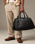 Luxury black leather weekender bag for men with structured base, dual carry handles and large travel compartment