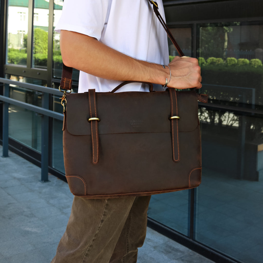 Man carrying a brown handmade leather messenger bag with a shoulder strap, showcasing its vintage design.