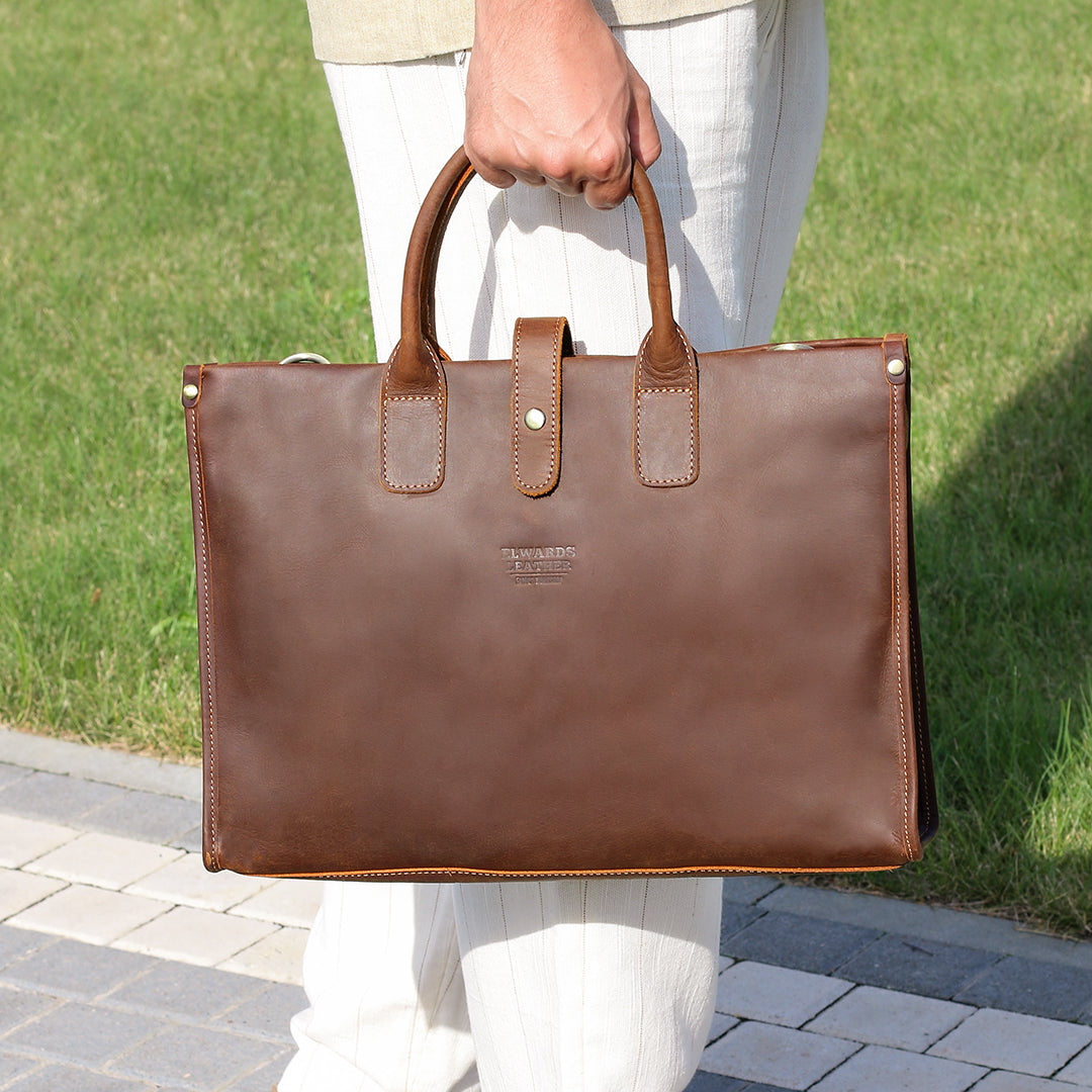 Man holding a luxury brown leather work bag with reinforced handles, showcasing its professional and vintage design.