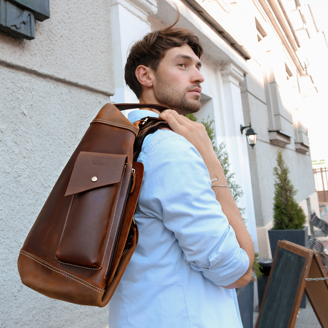 Man wearing a crossbody leather bag in an urban setting, highlighting its unique silhouette and practicality