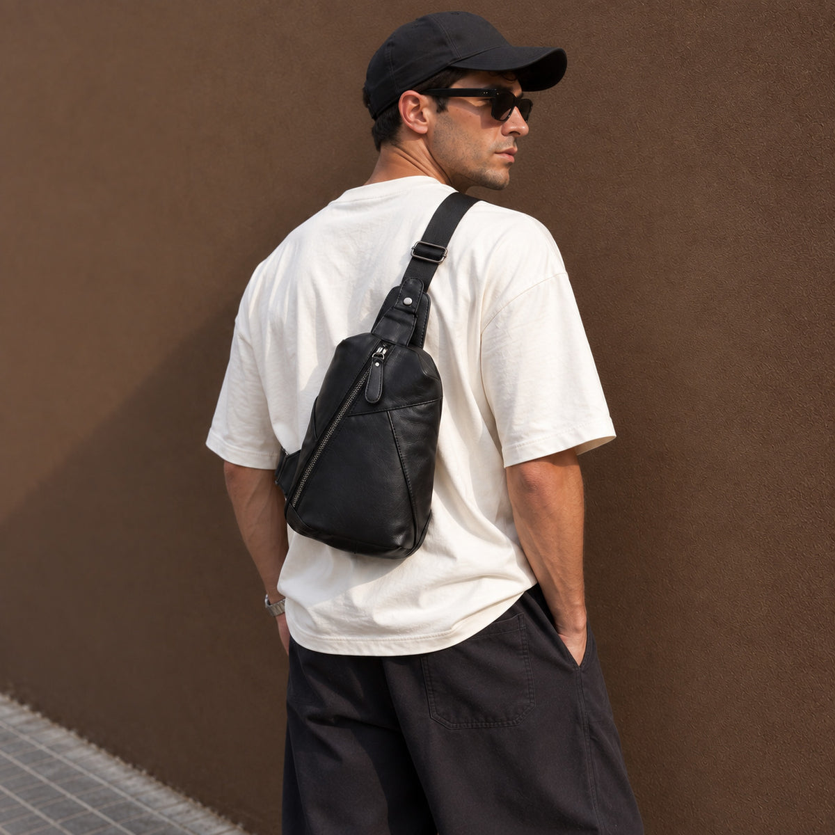 Men wearing a black full-grain leather sling bag across his back