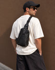 Men wearing a black full-grain leather sling bag across his back