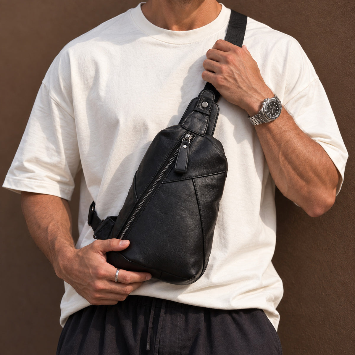 Men wearing a black full-grain leather sling bag with a white T-shirt