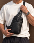 Men wearing a black full-grain leather sling bag with a white T-shirt