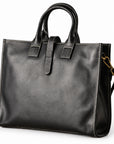 Men's black full-grain leather tote bag at an angle showing the stitched front and narrow side gusset