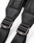 Close-up of a black camera strap with textured faux leather webbing and silver metal quick-release buckles on a white background.