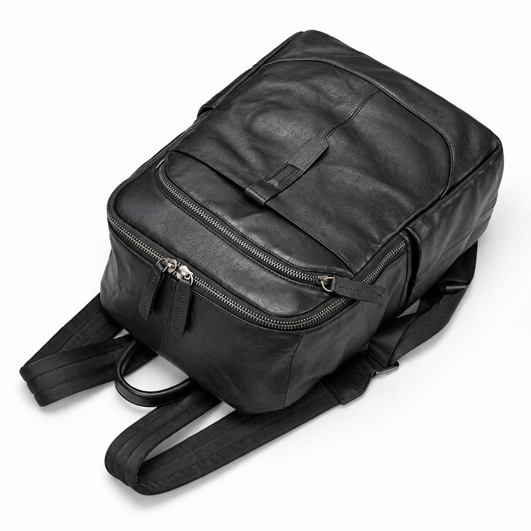 A black leather backpack with multiple zippered compartments and padded shoulder straps, photographed on a clean white background.