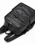 A black leather backpack with multiple zippered compartments and padded shoulder straps, photographed on a clean white background.
