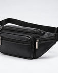 Black genuine leather fanny pack with multiple zippered compartments and an adjustable black webbing strap, shown on a light gray studio background.