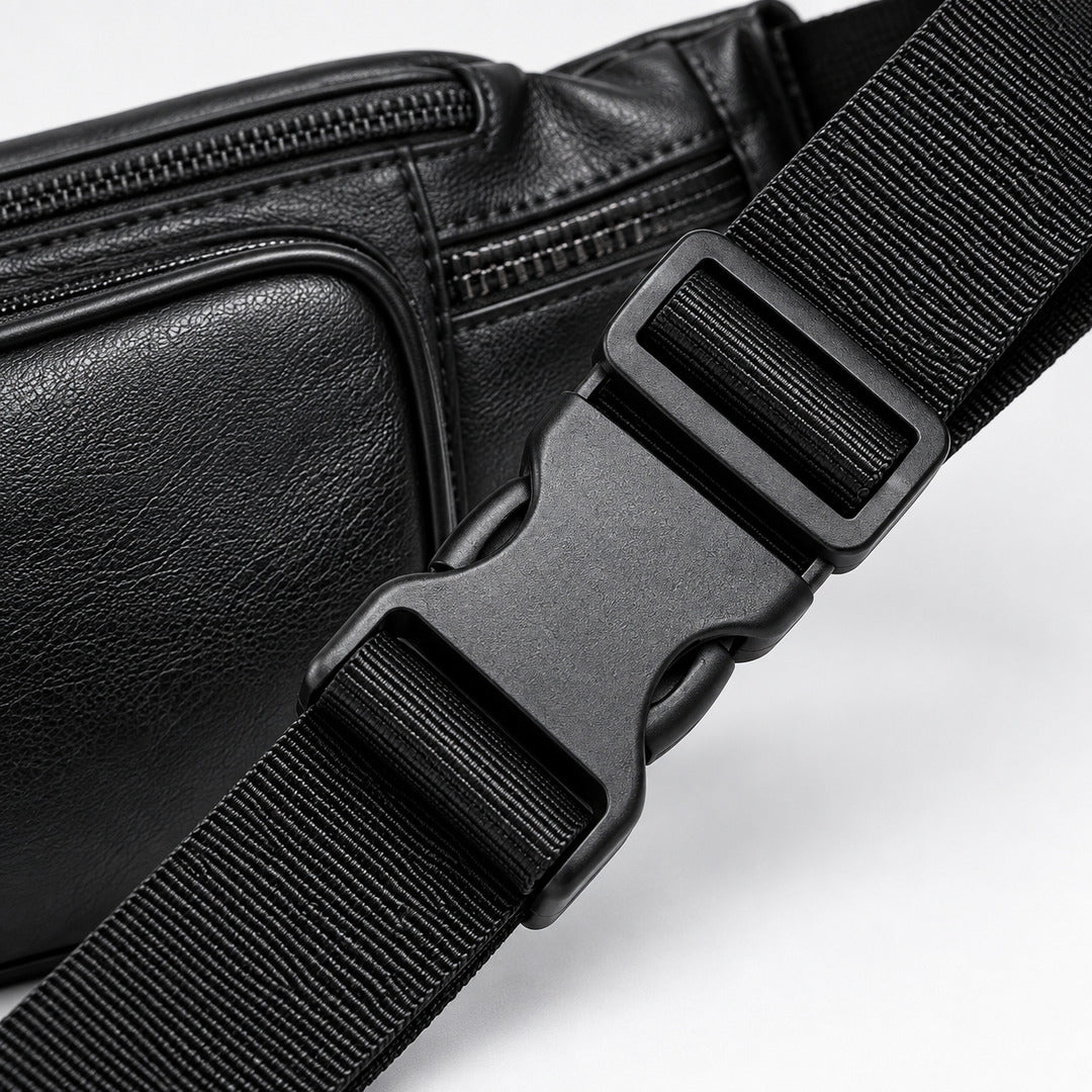 Close-up of a black leather crossbody bag with a matching black adjustable webbing strap and plastic quick-release buckle on a white background.