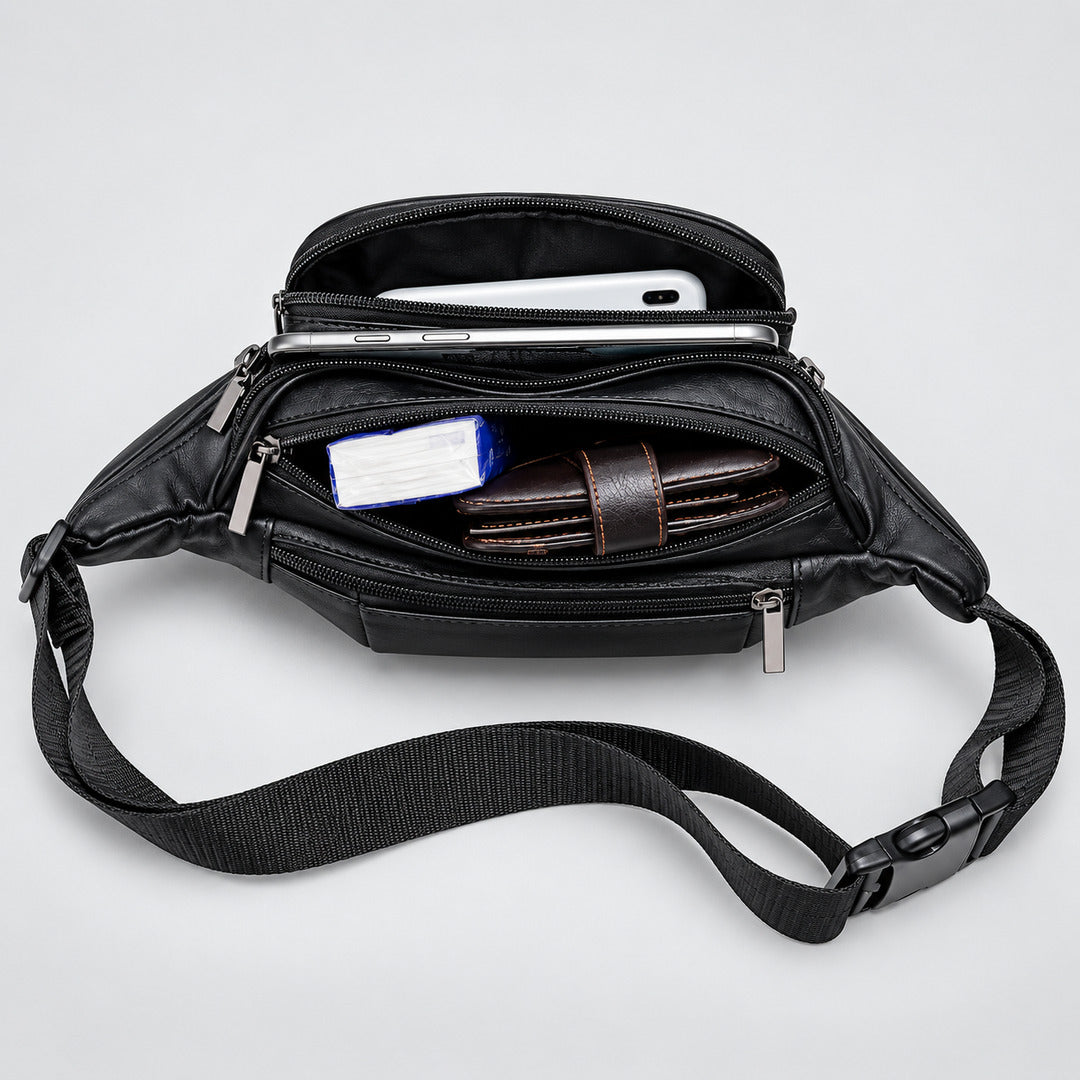 Black leather crossbody bag shown open from above, with multiple zip compartments and a wide adjustable strap. A white smartphone, brown wallet, and small blue item are visible inside on a light gray studio background.