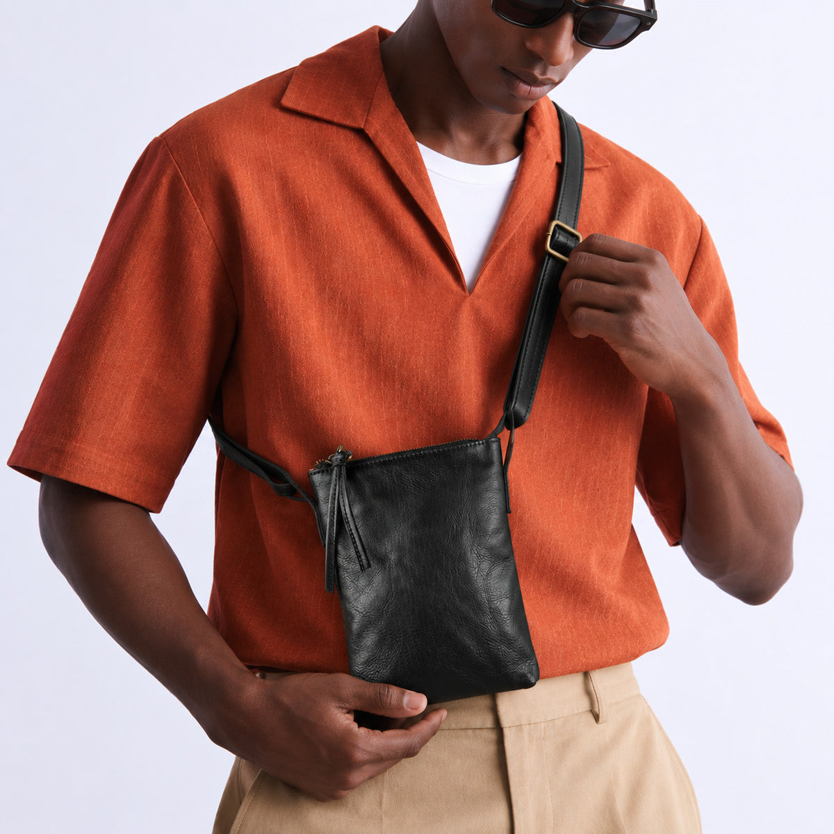 Close-up of a black leather crossbody bag with an adjustable shoulder strap
