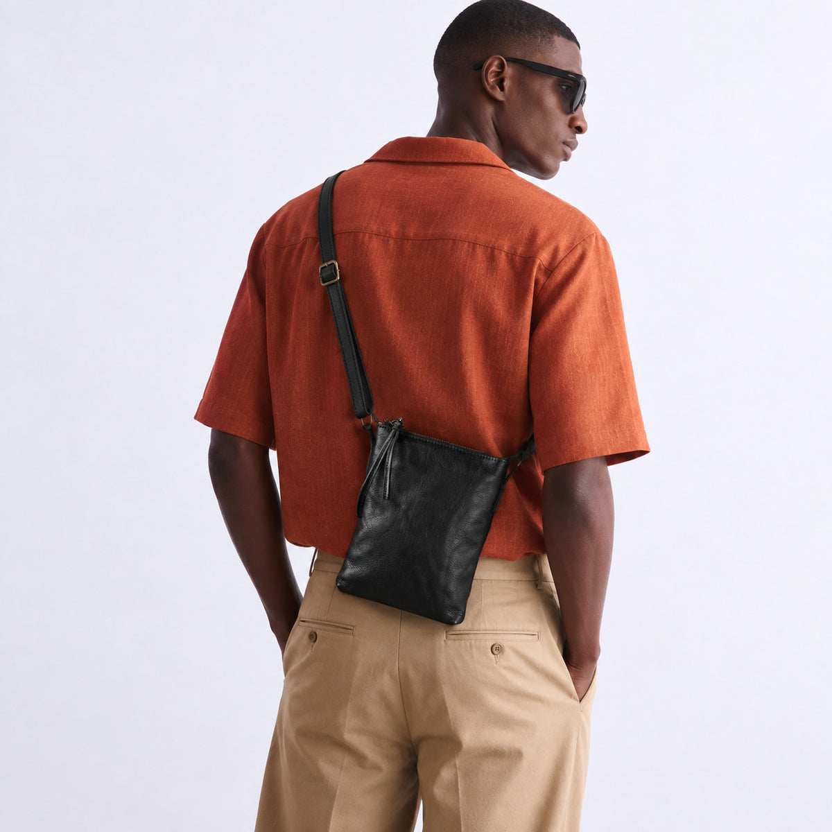 Back view of a man wearing a black leather crossbody bag over the shoulder