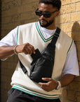 Man opening the front pocket of a black leather crossbody sling bag