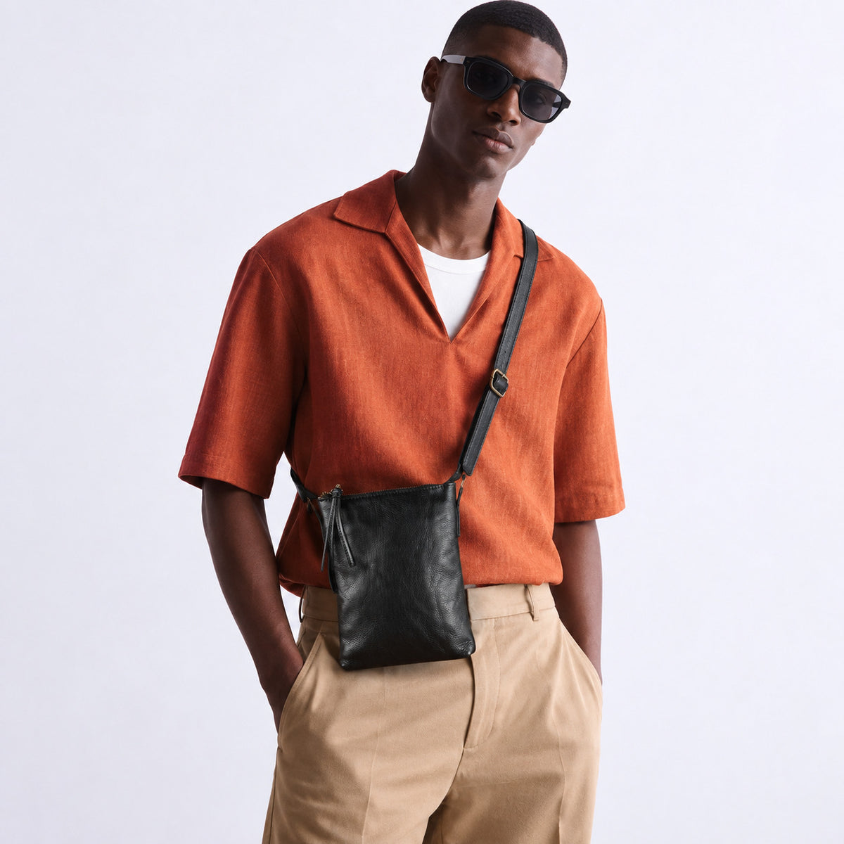 Man wearing a black leather crossbody bag with an adjustable shoulder strap
