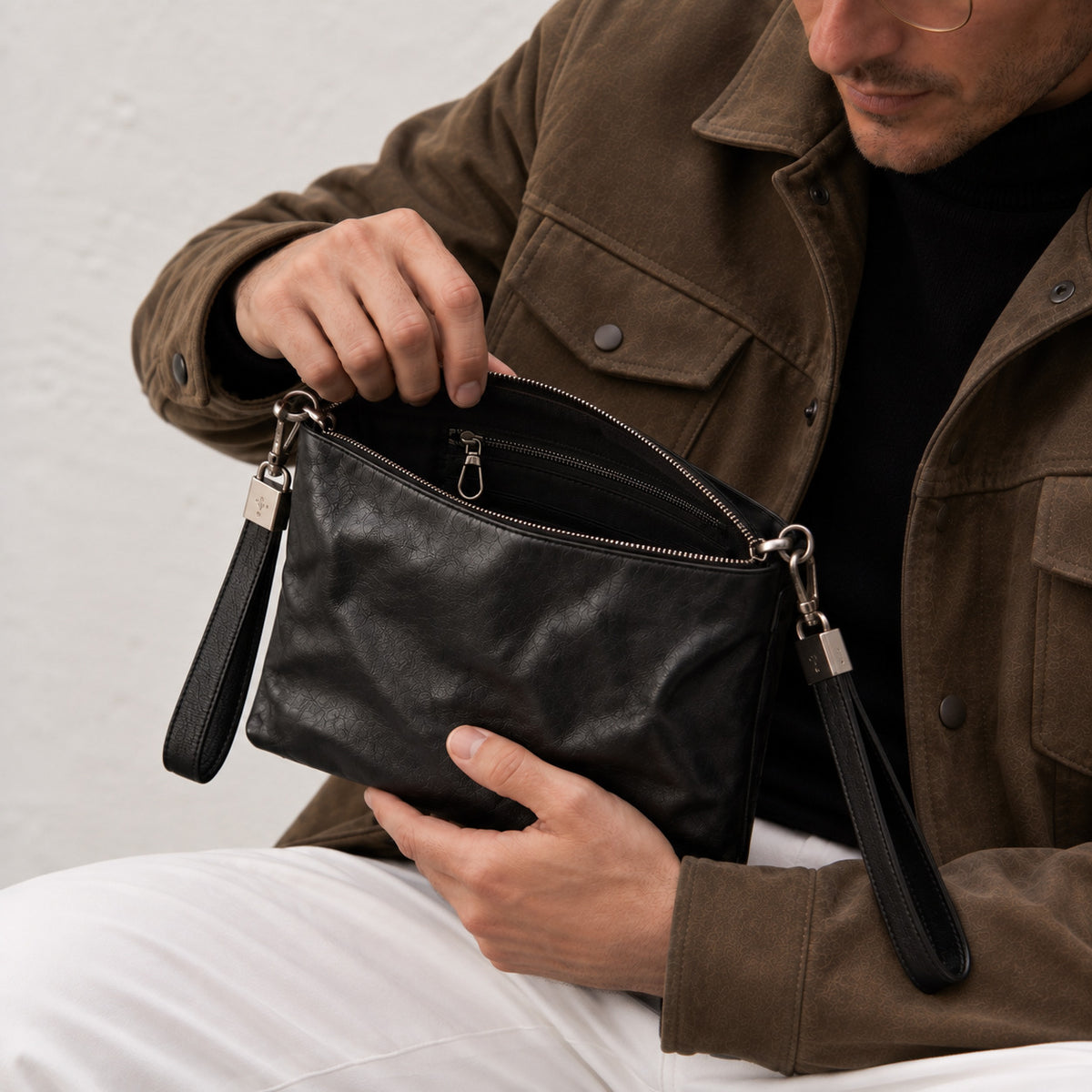 Open black leather crossbody bag showing zip closure and interior zipper pocket