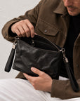 Open black leather crossbody bag showing zip closure and interior zipper pocket