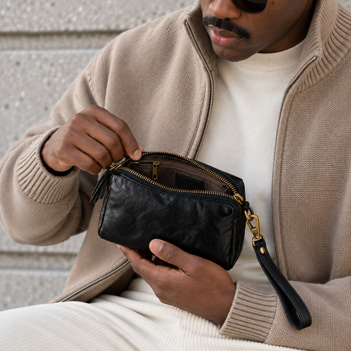 Close-up of a black leather crossbody bag with gold zipper and interior zip pocket
