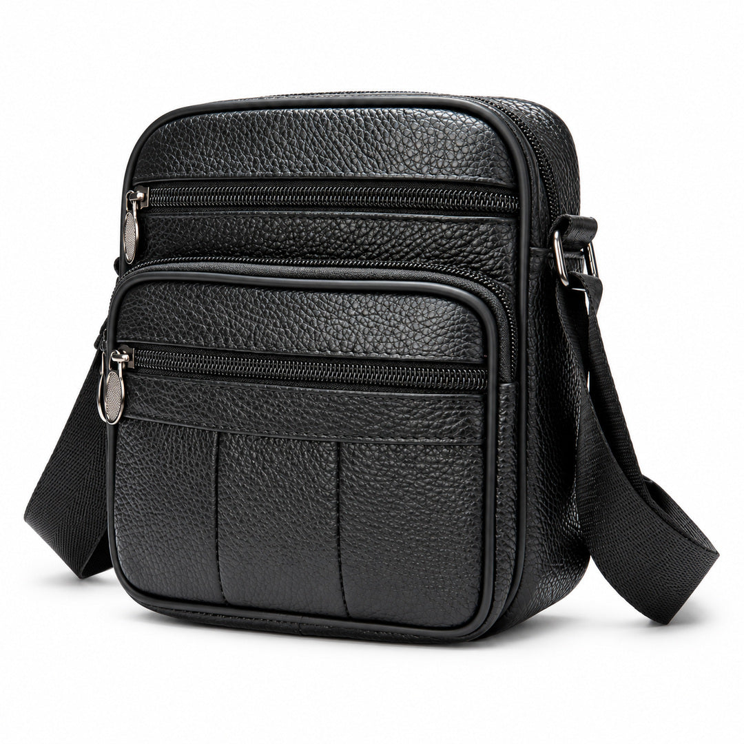Black pebbled leather crossbody bag with multiple zippered compartments and a wide adjustable shoulder strap, shown on a clean white background.