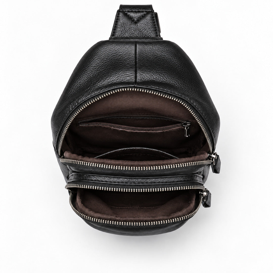 Black pebbled leather crossbody bag shown open from a top-down view, revealing a dark brown interior with multiple zippered compartments and a silver zipper.