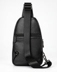 Black textured leather sling bag with a wide adjustable shoulder strap, shown from the back on a white studio background.