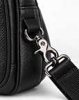 Close-up of a black pebbled leather bag with a silver metal clasp and a black webbed strap on a white background.