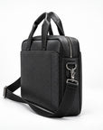 A black textured leather briefcase-style bag with dual top handles, a front slip pocket, a side zip closure, and an adjustable shoulder strap with silver-tone hardware, photographed on a clean white studio background.
